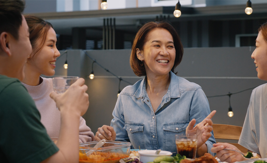 Middle aged woman talks and smiles at a dinner table