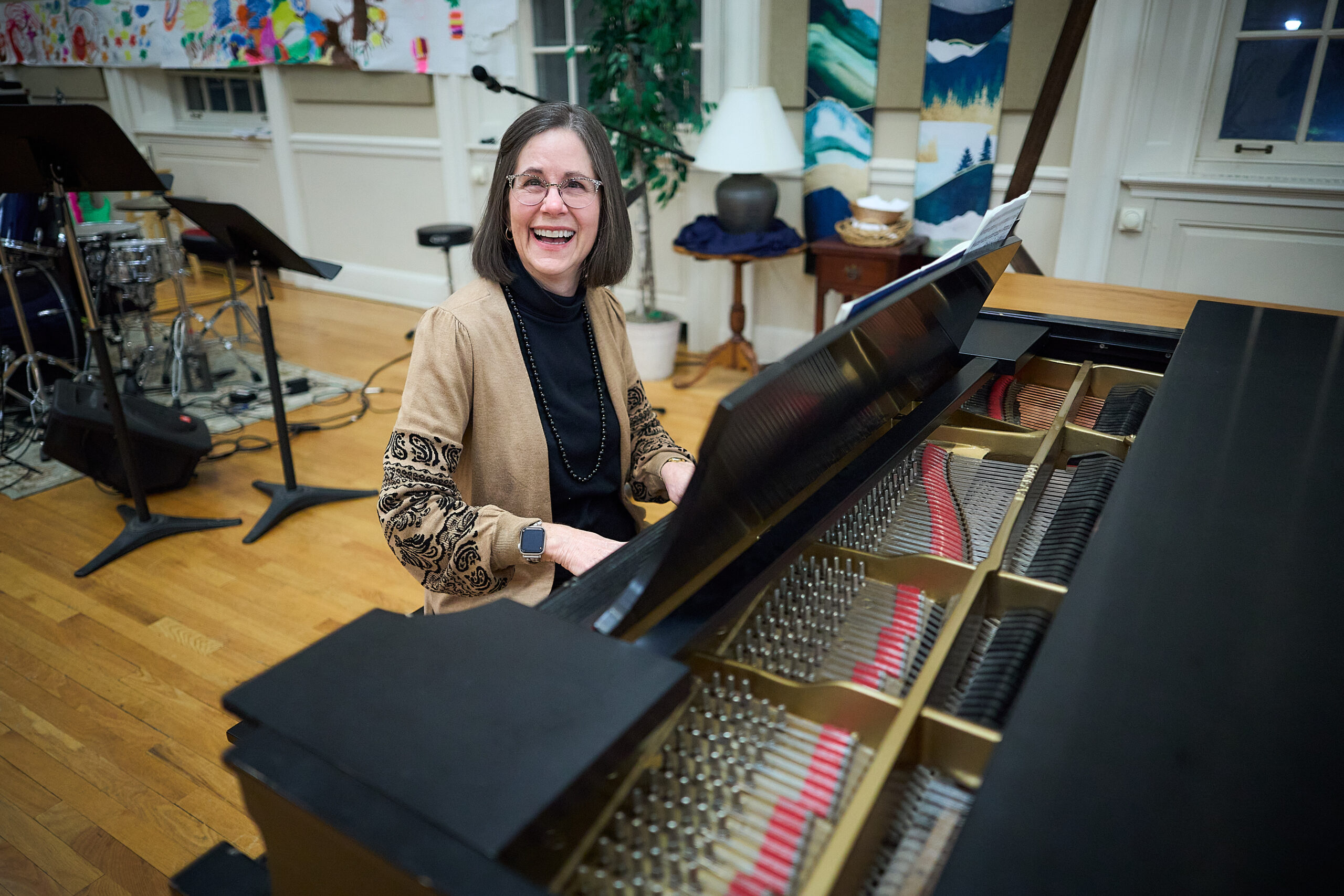 a woman is sitting in front of a piano, smiling for the camera.