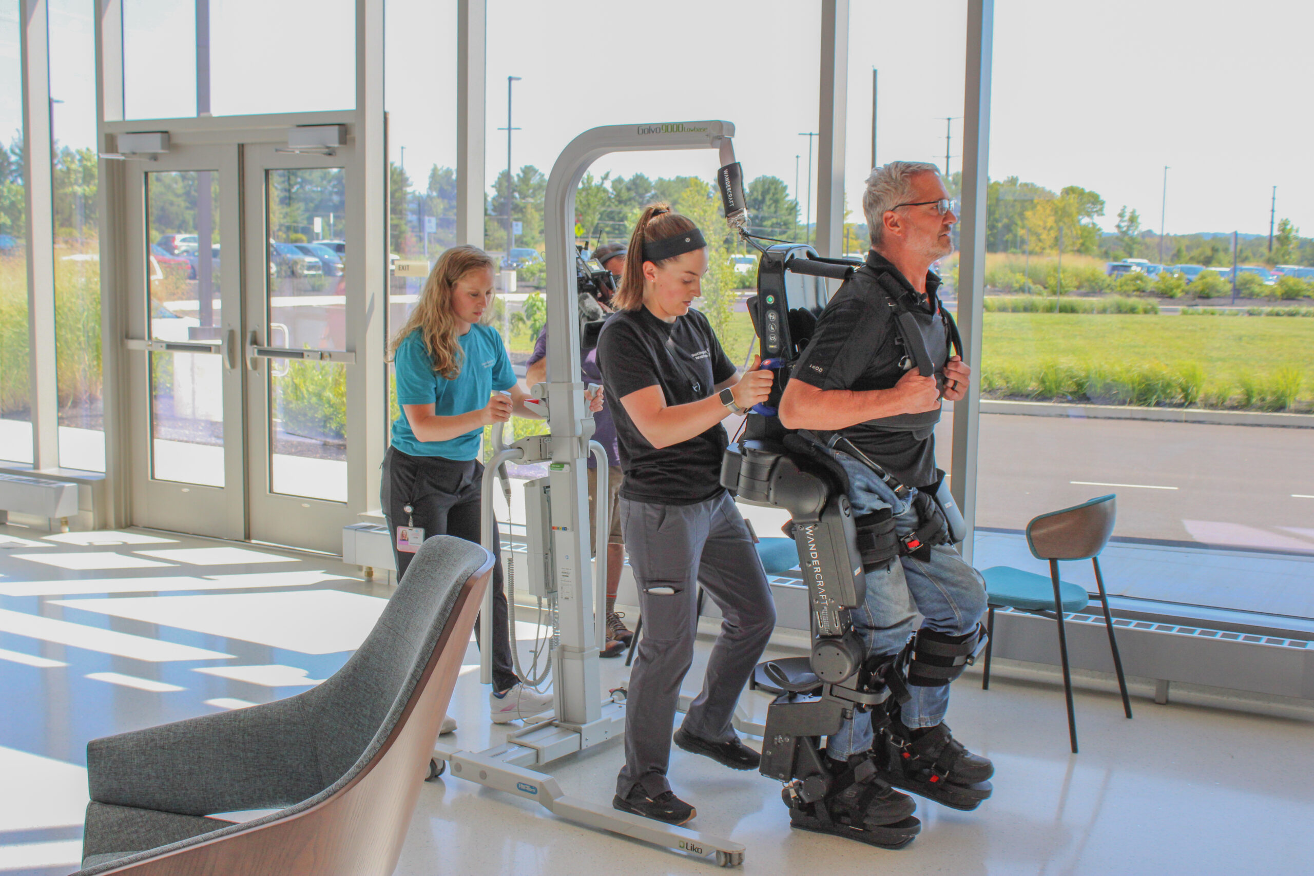 A person walks in the Wandercraft robotic exoskeleton technology with support from trained clinicians